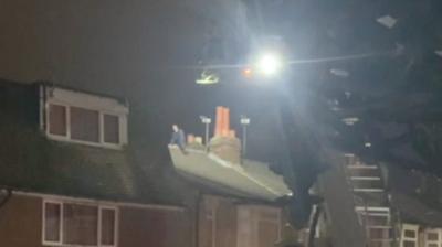 Man on a house roof and an aerial ladder platform