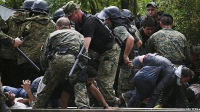 Two men squeezing through police line