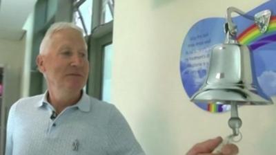 Man ringing a bell hanging from a hospital wall