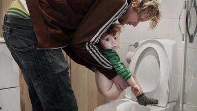 Man holding child over loo