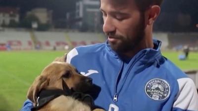 A football player holding a puppy