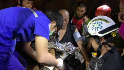 A monk is surrounded by rescue workers inside the cave