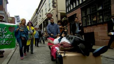 Mark Thomas pushed a bed during a protest march in Chester