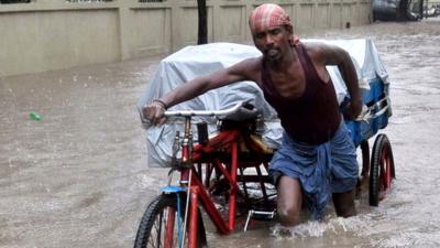 An Indian labourer pushes his cycle trishaw through floodwaters in Chennai