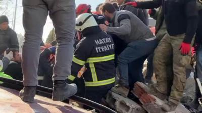 Rescuers carry a woman from the rubble