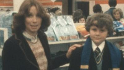 A BBC presenter with a schoolboy, discussing the cost of a school uniform