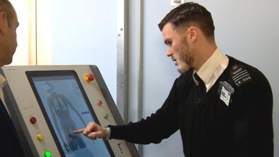 Prison officer pointing at body scanner