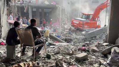 People sit amongst destroyed buildings in Gaza