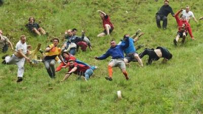 Competitors take part in the annual unofficial cheese rolling race at Cooper's Hill in Brockworth