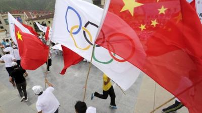 People waving Chinese and Olympics flags