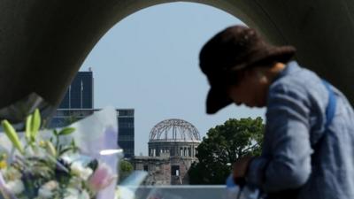 An elderly woman prays front of the monument for atomic bomb victims at the Hiroshima Peace Memorial Park