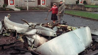 man and woman look at part of plane in road