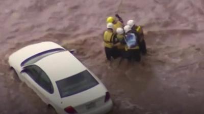 Emergency crews are shown rescuing a driver from his car.