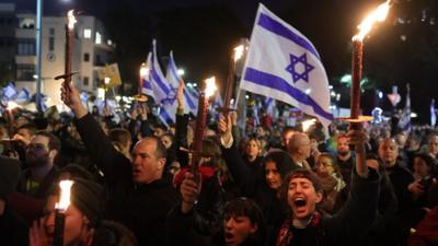 Protesters waving Israeli flags and holding candles