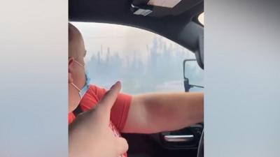 Person points out window driving through smoke-filled route