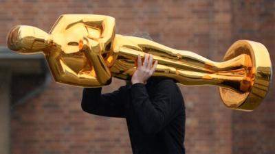 Man carrying giant Oscar statue