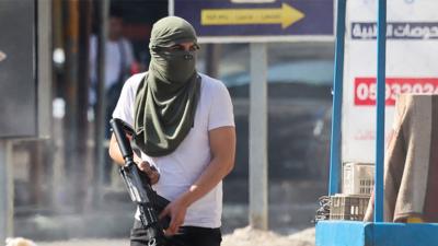 An armed Palestinian militant takes up a position during a confrontation with Israeli army in Jenin