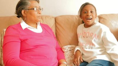 a-young-black -girl-sits-with-her-grandma-on-a-leather-sofa