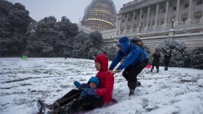 Family in Washington DC pushing a sled in the snow.