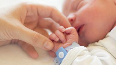 A baby holding its parent's hand