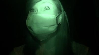 A night vision still of Carmen Roberts watching a zombie inspired horror experience