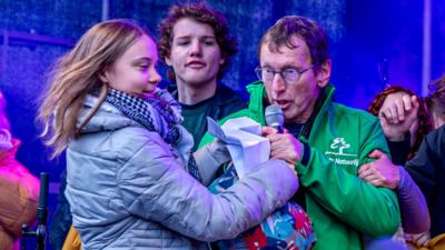 A man grabs the microphone from Greta Thunberg at a large climate protest in Amsterdam