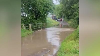 Cars waiting at a flooded ford in Holme Hale, Norfolk.