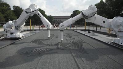 Two robots drawing in grey sand in Ueno Park, Tokyo