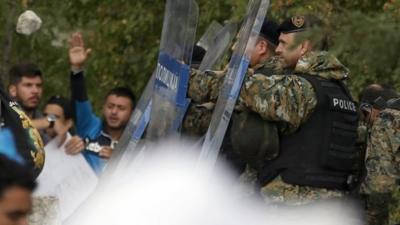 Macedonian riot police officers clash with migrants