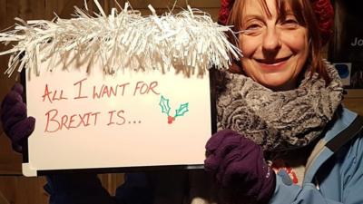 Woman holding sign saying 'All I want for Brexit is'