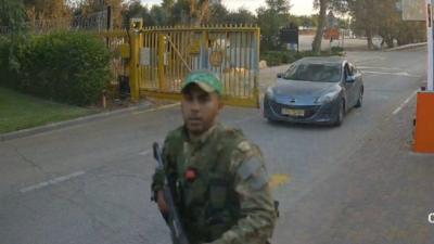 Hamas militants walk into a kibbutz community after ambushing a car at the gates.