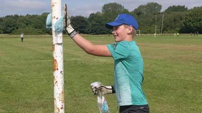 boy cleaning goal post.