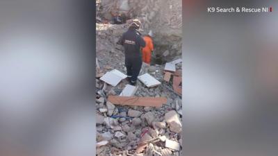 Rescuers watch search dog Delta as she sniffs an area where a woman was trapped