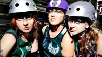 Three roller derby skaters look