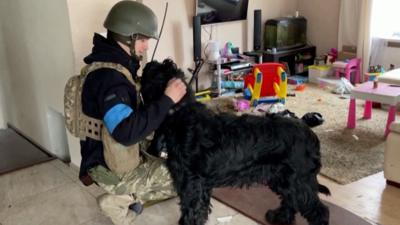 A Ukrainian Soldier strokes a black dog