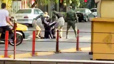 A woman getting arrested in the middle of a road in Iran