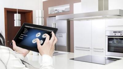 Woman using tablet to control kitchen appliances