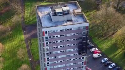 Footage captured by a drone camera shows the damage caused to a tower-block in Dunmurry, County Antrim