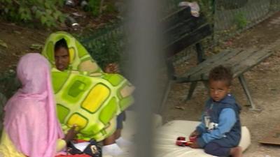 Two women and a child on a mattress in a park in Paris