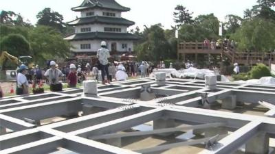 Main tower of Hirosaki Castle in background with temporary frame, where the tower will be moved to, in the foreground