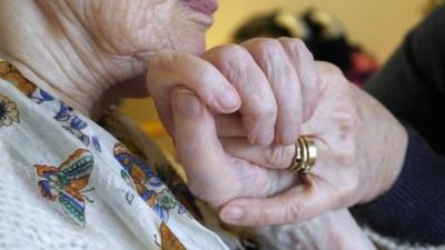 Woman with Alzheimer's disease holding hands with a carer