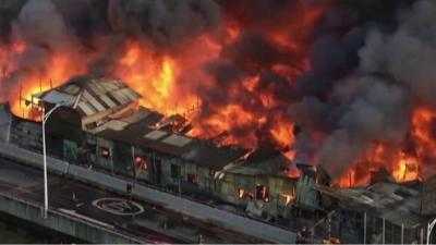 Building engulfed by fire, with thick smoking billowing into the air