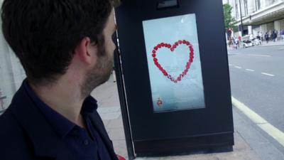 A man looking at poster which can change depending on how people respond to it