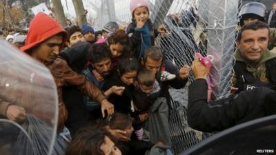 A Syrian refugee family prepares to cross the Greek-Macedonian border through a metal border fence near the village of Idomeni