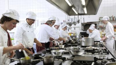 Group of cooks in a commercial kitchen for a programme on the phrase 'too many cooks spoil the broth'