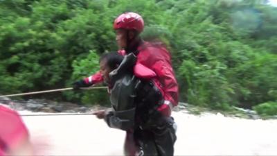 A rescuer helps a man navigate the floodwaters