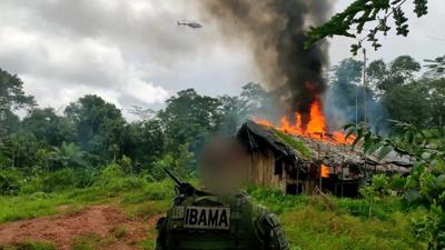 IBAMA officer in front of burning building