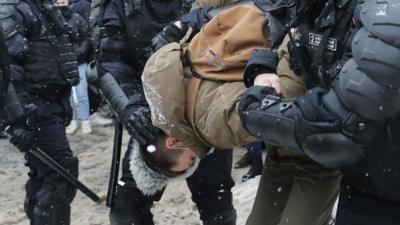 Protester held by police officers