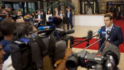 Greek Prime Minister Alexis Tsipras, right, speaks with the media as he leaves after a meeting of eurozone heads of state at the EU Council building in Brussels on Monday, July 13, 2015.