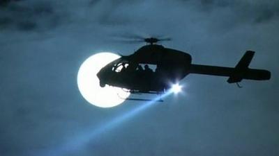 Helicopter silhouetted against Moon